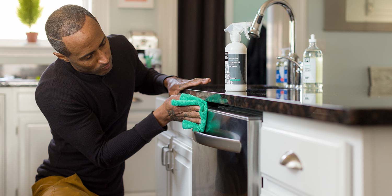 An man scrubbing the front of a dishwasher with Better Life's Stainless Steel Polish