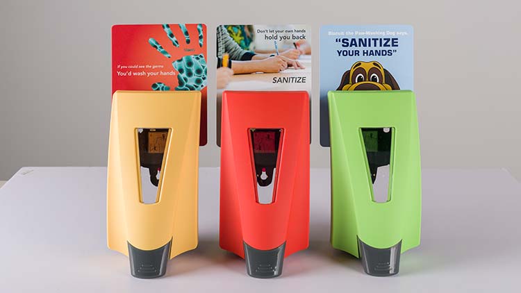 A set of three symmetry dispensers, yellow, red, and green, with different placards behind them