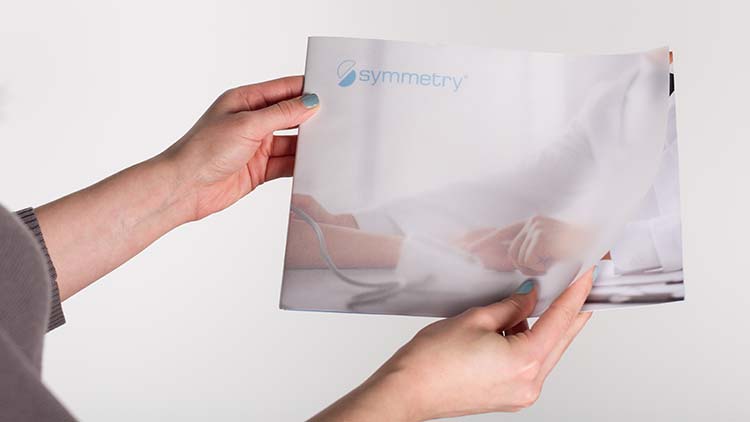 The front cover of a Symmetry pamphlet showing a doctor's hands